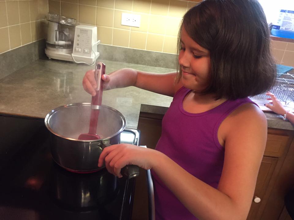 Young girl stirring something in a pot