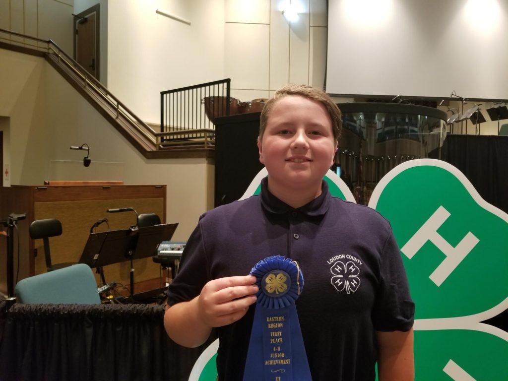 Young man holding a blue ribbon for a 4-H contest